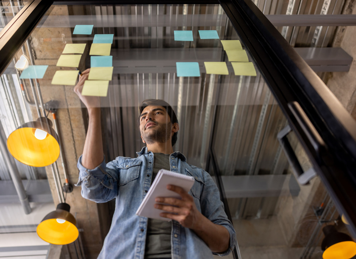 Office worker writing on transparent board