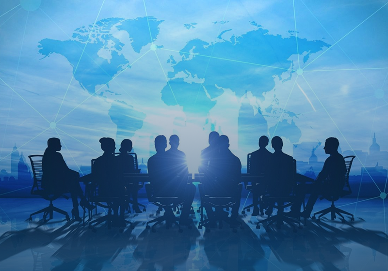 Silhouetted business team meeting with world map backdrop.