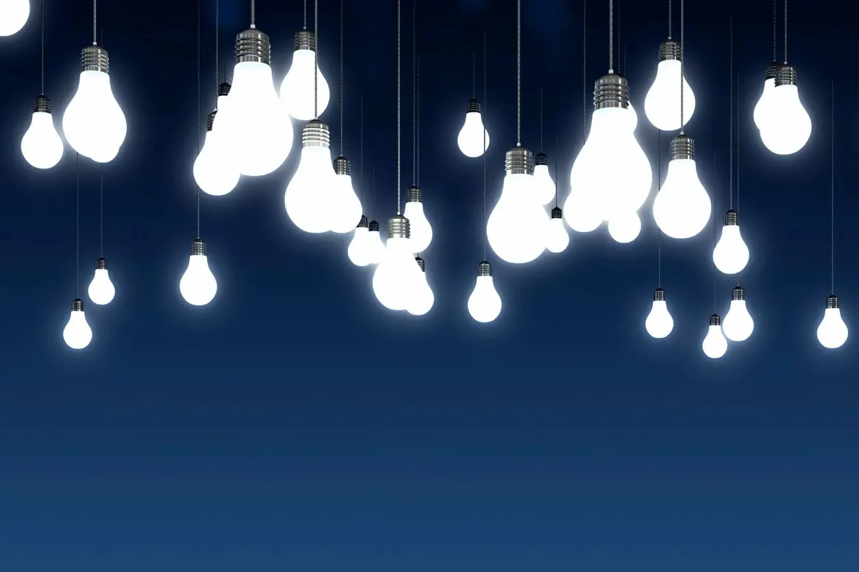 Cluster of glowing light bulbs hanging against a dark blue background.