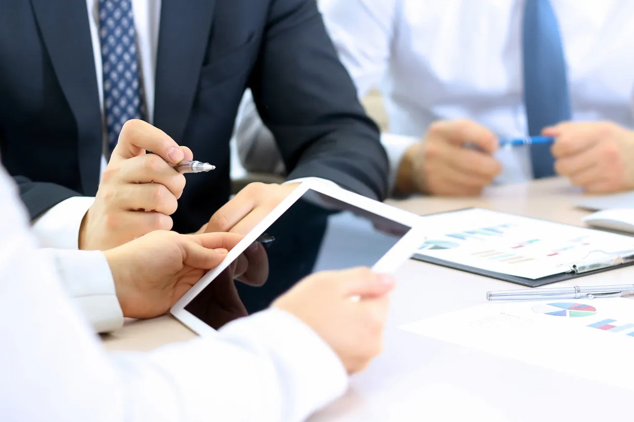 Business professionals using a tablet during a meeting.