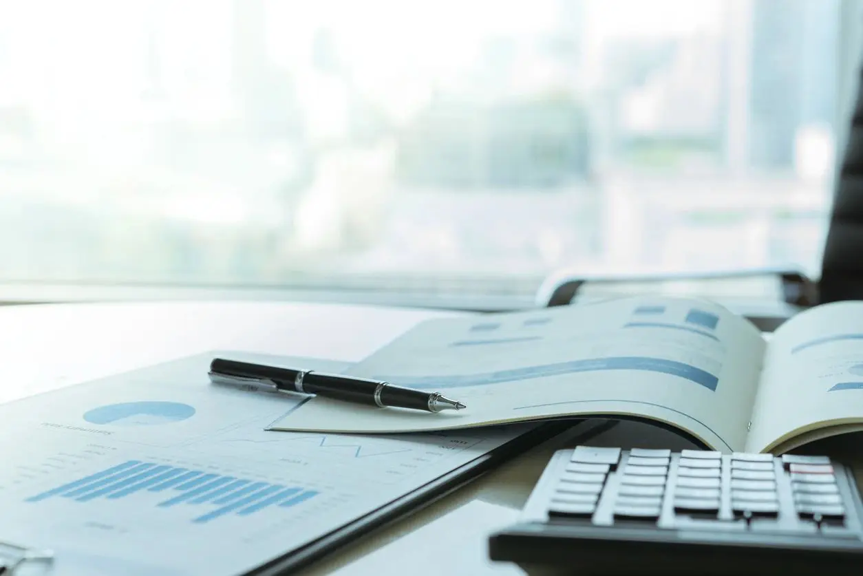Pen resting on open financial documents with a calculator nearby.