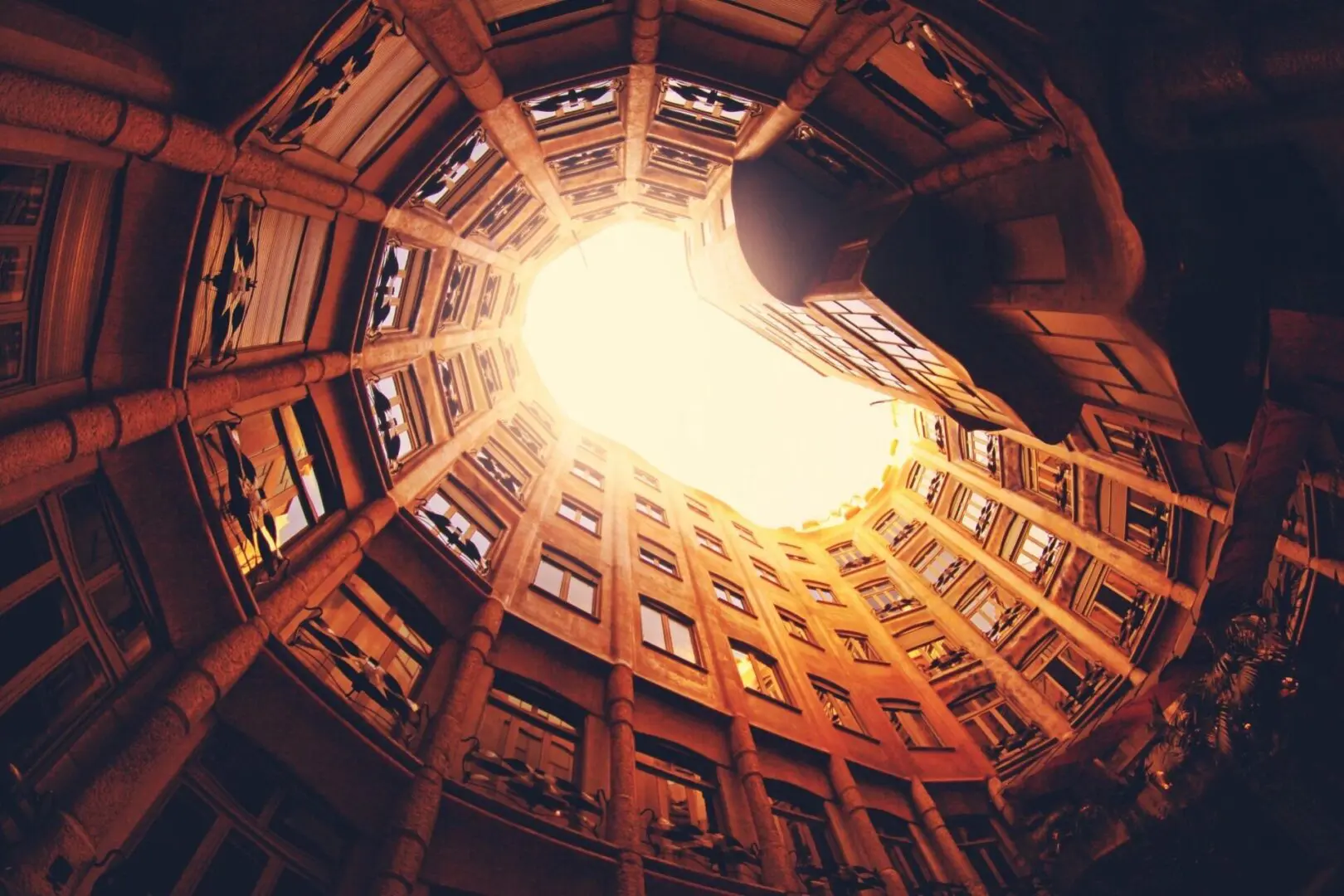 Looking up inside a circular, multi-story building with bright light overhead.
